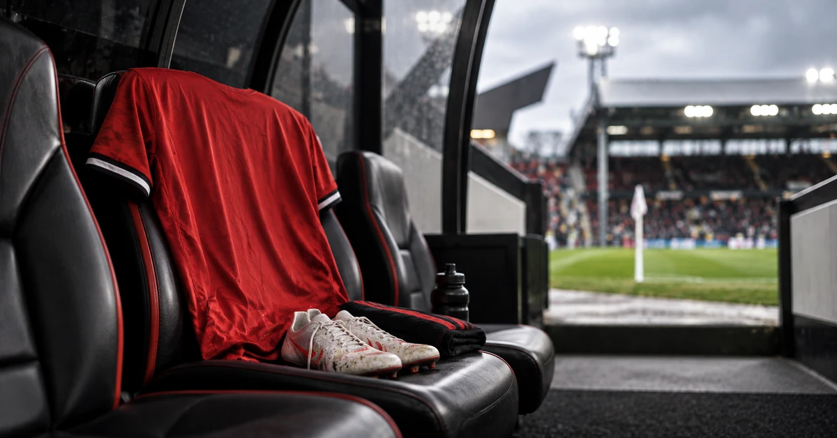 Editorial illustration of an empty red football shirt and boots on a dugout seat beside a pitch, representing a Manchester United attacking absence at Fulham.